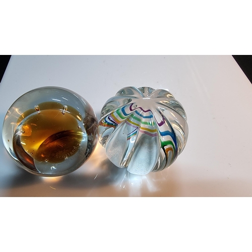 324 - Two Caithness glass paperweights, one inset with a clock with multicolour ribbon design. The other i... 