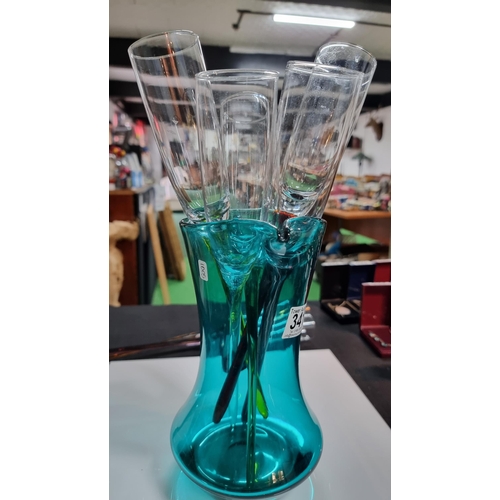 341 - Art glass green jug containing 9x vintage long harlequin stemmed champagne flutes, has no bases and ... 