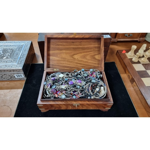 386 - Solid Mahogany box with brass mounts complete with a large quantity of costume jewellery. Height 9.5... 