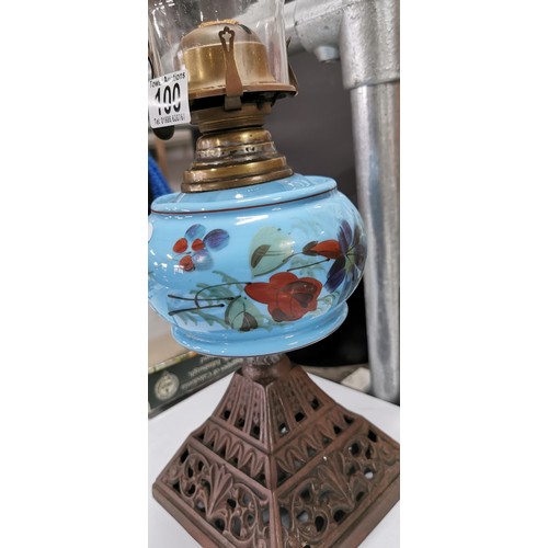 100 - Vintage handpainted blue glass oil lamp on a cast iron base comes with a glass chimney, missing a ga... 