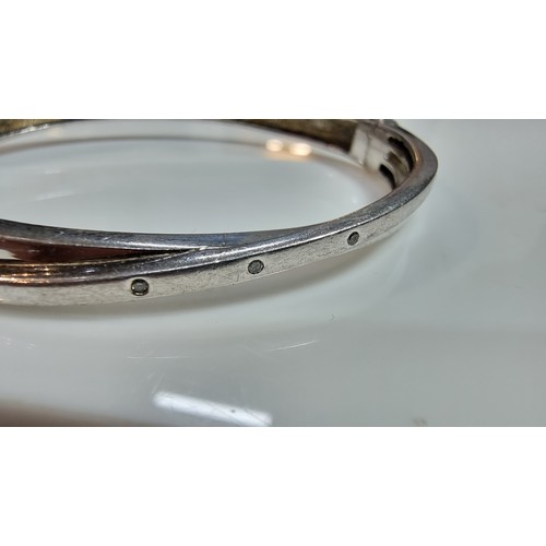 346 - 925 silver hinged bangle with a crossover design inset with three small genuine diamond stones marke... 