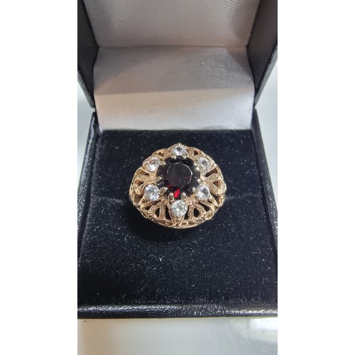 369 - hallmarked yellow gold ornate dress ring inset with a large garnet stone to the centre surrounded by... 