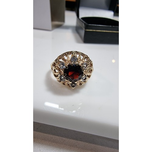 369 - hallmarked yellow gold ornate dress ring inset with a large garnet stone to the centre surrounded by... 