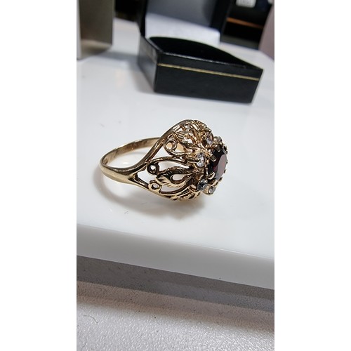 369 - hallmarked yellow gold ornate dress ring inset with a large garnet stone to the centre surrounded by... 