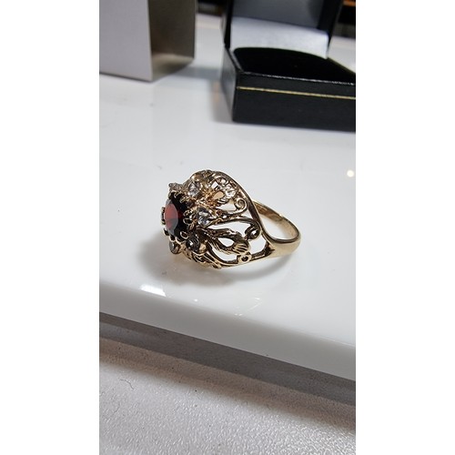 369 - hallmarked yellow gold ornate dress ring inset with a large garnet stone to the centre surrounded by... 