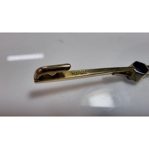 371 - 9ct gold and silver bar brooch inset with a pretty blue glass stone to the centre and white clear st... 