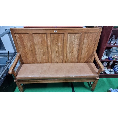 490 - Antique pitch pine settle with a paneled back inc a fitted upholstered cushion in good overall condi... 