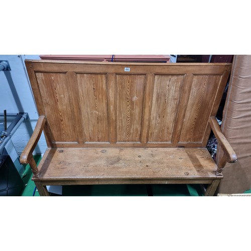 490 - Antique pitch pine settle with a paneled back inc a fitted upholstered cushion in good overall condi... 