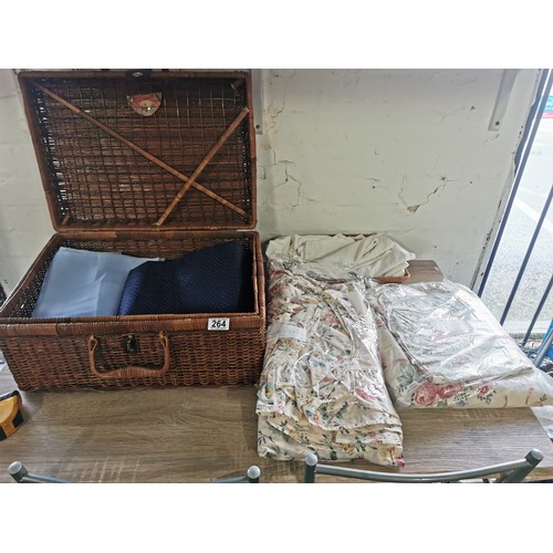 264 - A wicker picnic basket along with a wicker tray. Containing two double duvet cover and pillow cases,... 