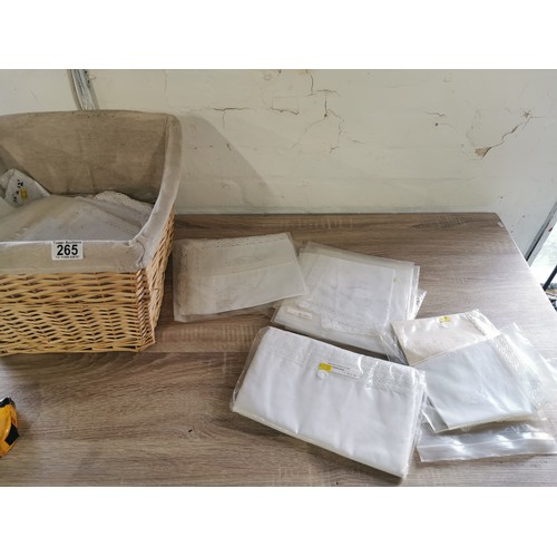265 - A wicker lined linen basket, containing a quantity of traced needle work, table cloths, table centre... 
