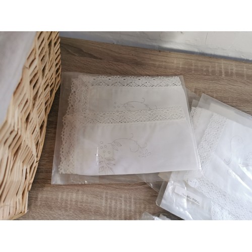 265 - A wicker lined linen basket, containing a quantity of traced needle work, table cloths, table centre... 