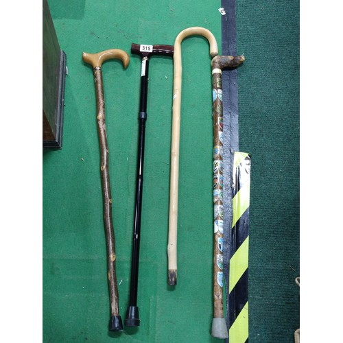 315 - A collection of 4 walking sticks including a collapsible mobility aid stick, one contains a large qu... 