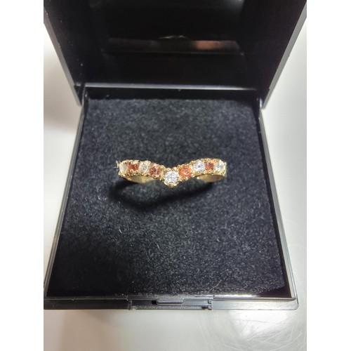 405 - A hallmarked 9ct yellow gold wishbone ring inset with orange and white cz crystal stones. In excelle... 