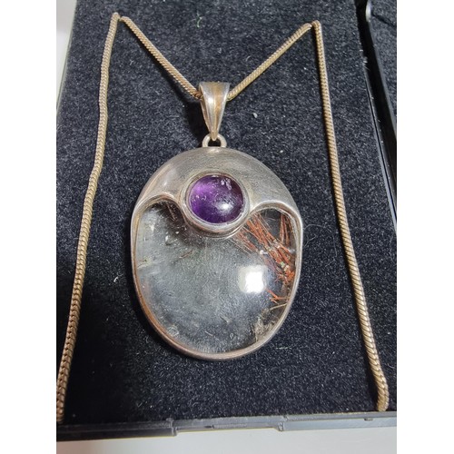 371 - An ornate 925 silver pendant inset with a large oval rutilated quartz stone and an amethyst cabochon... 