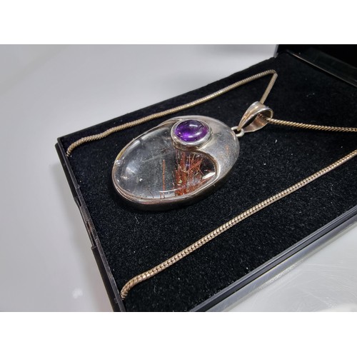 371 - An ornate 925 silver pendant inset with a large oval rutilated quartz stone and an amethyst cabochon... 