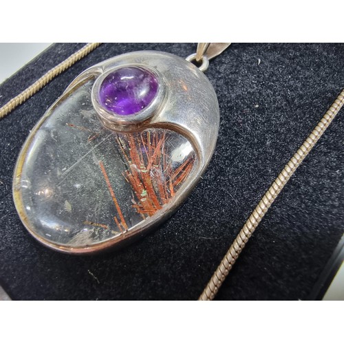 371 - An ornate 925 silver pendant inset with a large oval rutilated quartz stone and an amethyst cabochon... 