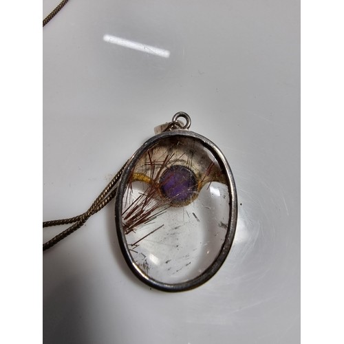 371 - An ornate 925 silver pendant inset with a large oval rutilated quartz stone and an amethyst cabochon... 