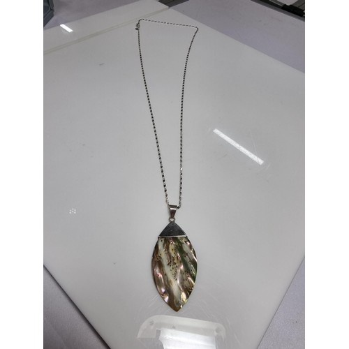 374 - A large 925 silver m.o.p. pendant with an unusual natural design, set on a very long 26