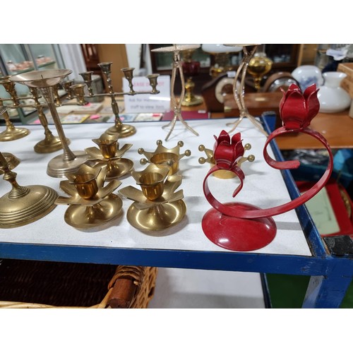 194 - A large quantity of various brass candlesticks all in a wicker basket with wooden handles.