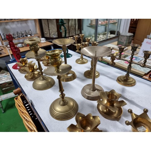 194 - A large quantity of various brass candlesticks all in a wicker basket with wooden handles.