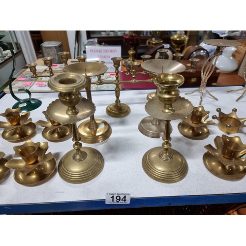 194 - A large quantity of various brass candlesticks all in a wicker basket with wooden handles.