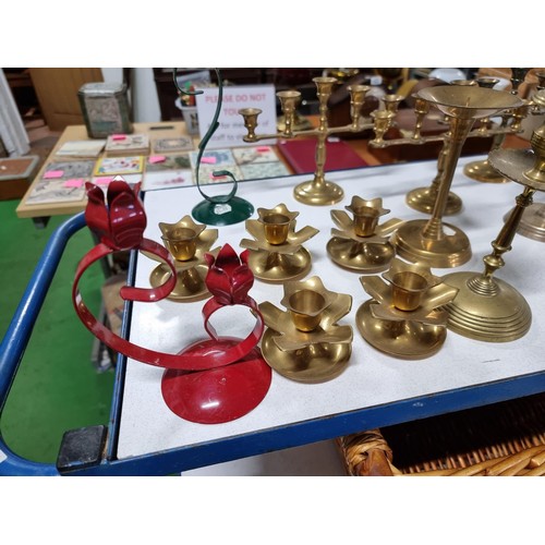 194 - A large quantity of various brass candlesticks all in a wicker basket with wooden handles.