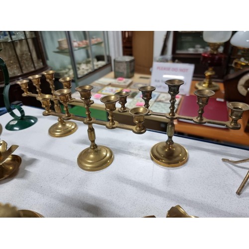 194 - A large quantity of various brass candlesticks all in a wicker basket with wooden handles.