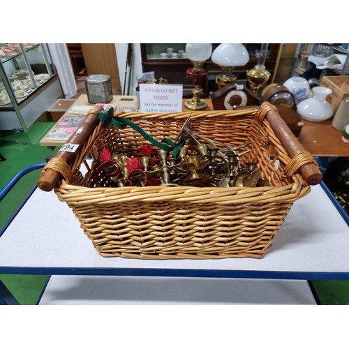 194 - A large quantity of various brass candlesticks all in a wicker basket with wooden handles.