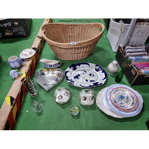 253 - Wicker basket full of odds including a masons platter, cruet sets, paperweights etc