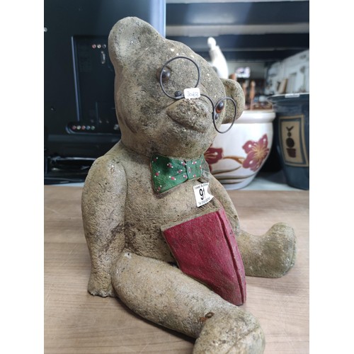 91 - A vintage stoneware teddy bear formed statue with book, reading glasses and dickiebow. The book read... 