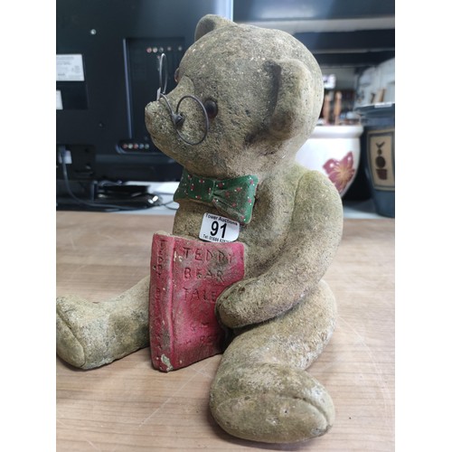 91 - A vintage stoneware teddy bear formed statue with book, reading glasses and dickiebow. The book read... 