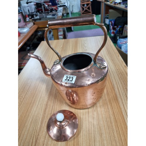 323 - A good quality antique copper kettle with a copper handle and a porcelain nob, in clean polished con... 