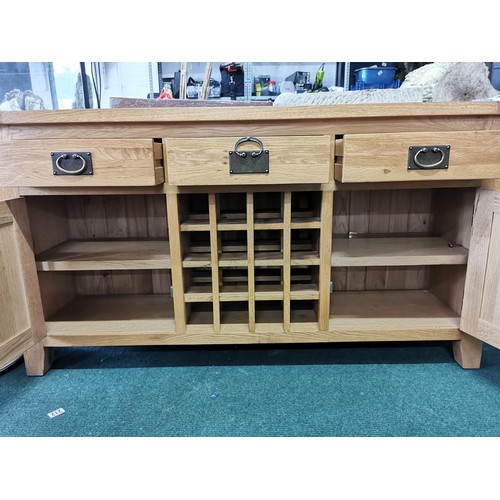 496 - A solid oak sideboard, 3 drawers over 2 doors with a 16 division wine rack in the middle, in good or... 