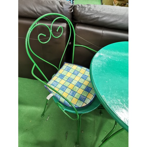 504 - Green metal bistro table complete with 2x wrought iron chairs with seat cushions, table folds flat f... 