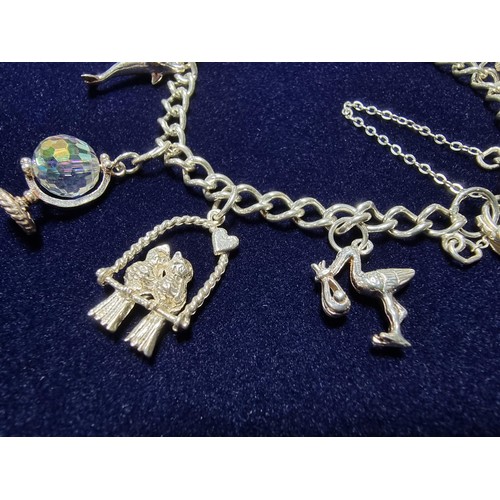 351 - A vintage 925 silver charm bracelet to include 10 silver charms and a silver heart padlock, includes... 