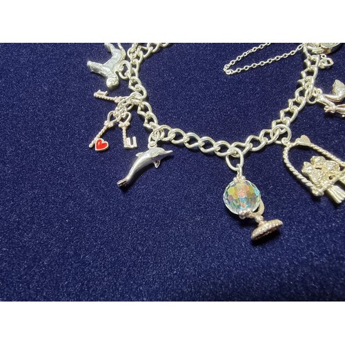 351 - A vintage 925 silver charm bracelet to include 10 silver charms and a silver heart padlock, includes... 