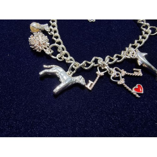 351 - A vintage 925 silver charm bracelet to include 10 silver charms and a silver heart padlock, includes... 