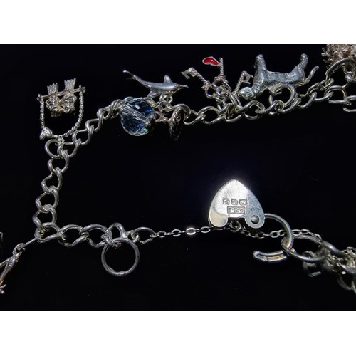 351 - A vintage 925 silver charm bracelet to include 10 silver charms and a silver heart padlock, includes... 