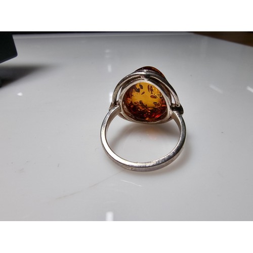 353 - A good quality 925 silver dress ring inset with a large oval Baltic amber stone presenting good oran... 