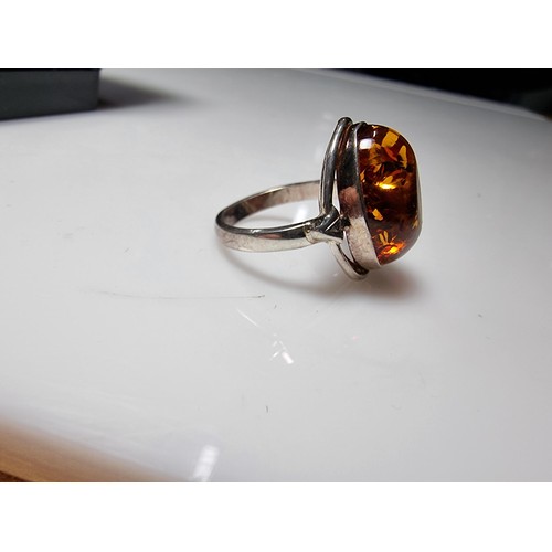 353 - A good quality 925 silver dress ring inset with a large oval Baltic amber stone presenting good oran... 