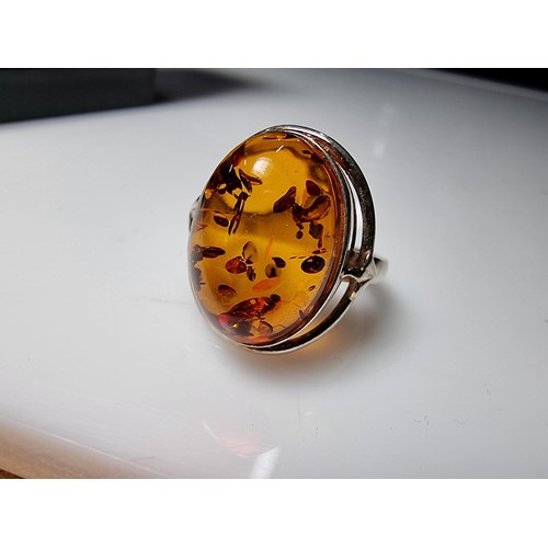 353 - A good quality 925 silver dress ring inset with a large oval Baltic amber stone presenting good oran... 