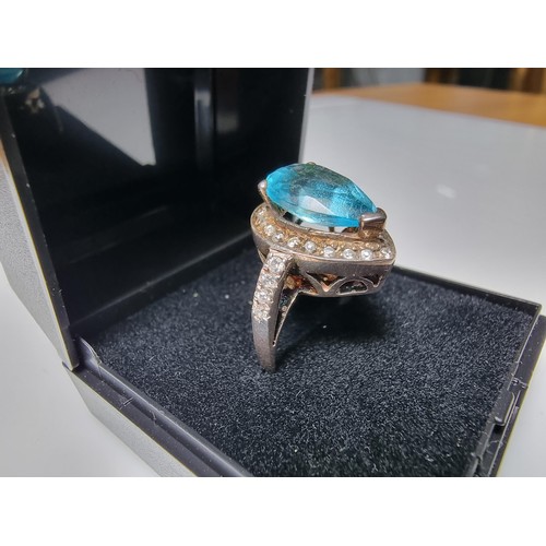 359 - An ornate 925 silver dress ring inset with a large blue glass stone surrounded by smaller CZ crystal... 