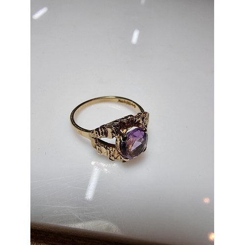 392 - A vintage 9ct hallmarked yellow gold ring with a bark effect, inset with a large faceted amethyst ge... 