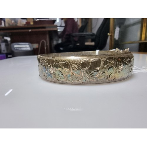 373 - A vintage hallmarked silver hinged bangle with an ornate engraved floral design to one side, complet... 