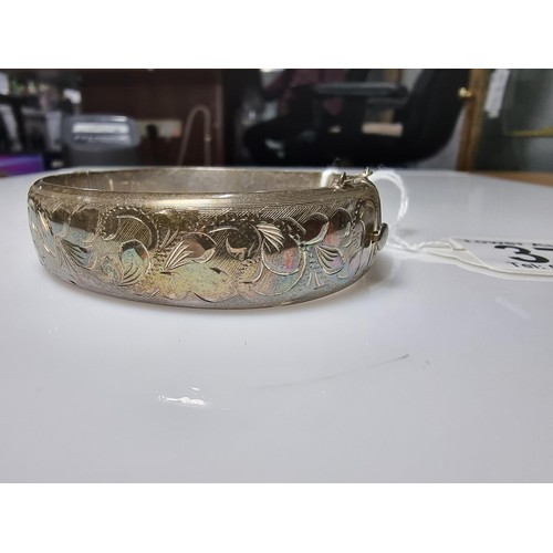 373 - A vintage hallmarked silver hinged bangle with an ornate engraved floral design to one side, complet... 