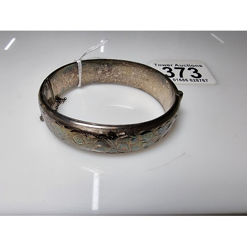 373 - A vintage hallmarked silver hinged bangle with an ornate engraved floral design to one side, complet... 