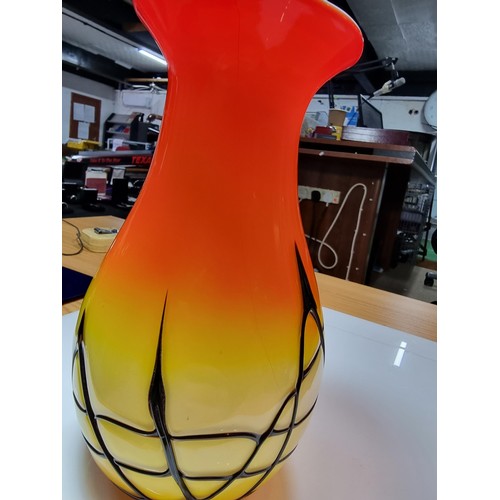 405 - A stunning art glass vase in sunset colours with an overlaid black web design to the base by an unkn... 