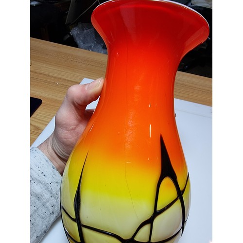 405 - A stunning art glass vase in sunset colours with an overlaid black web design to the base by an unkn... 