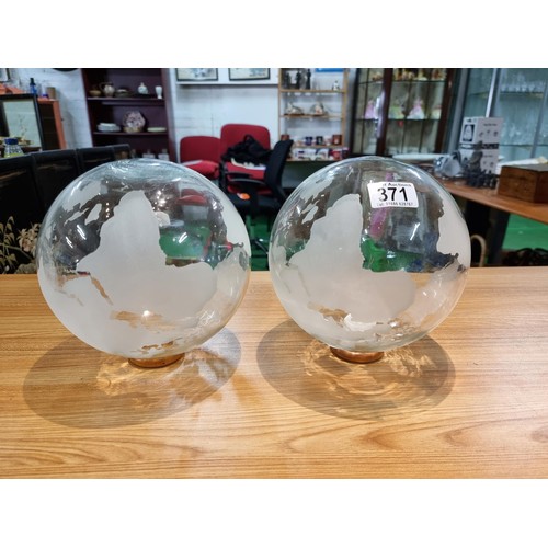 371 - A pair of decorative glass world globes on wooden stands, one inset with a battery operated tealight... 