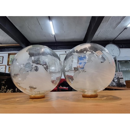 371 - A pair of decorative glass world globes on wooden stands, one inset with a battery operated tealight... 